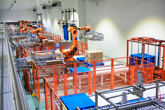 Industrial robotic arm automatically palletizing products inside an intelligent warehouse automation system
