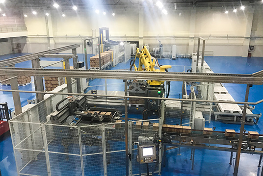 Industrial robotic arm protected by physical safety fence with emergency stop and interlock system