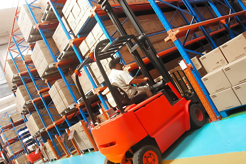 Drive-in pallet racking system with forklift loading pallets inside storage lanes