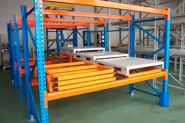Push back pallet racking system using inclined carts for high-density pallet storage.