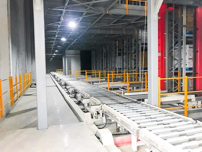 Conveyor lines in front of a stacker crane ASRS warehouse for automated pallet handling